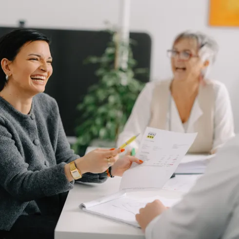 Zwei Frauen lachend am Tisch mit Papier auf dem Tisch