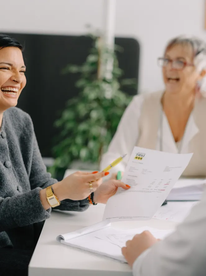 Zwei Frauen lachend am Tisch mit Papier auf dem Tisch