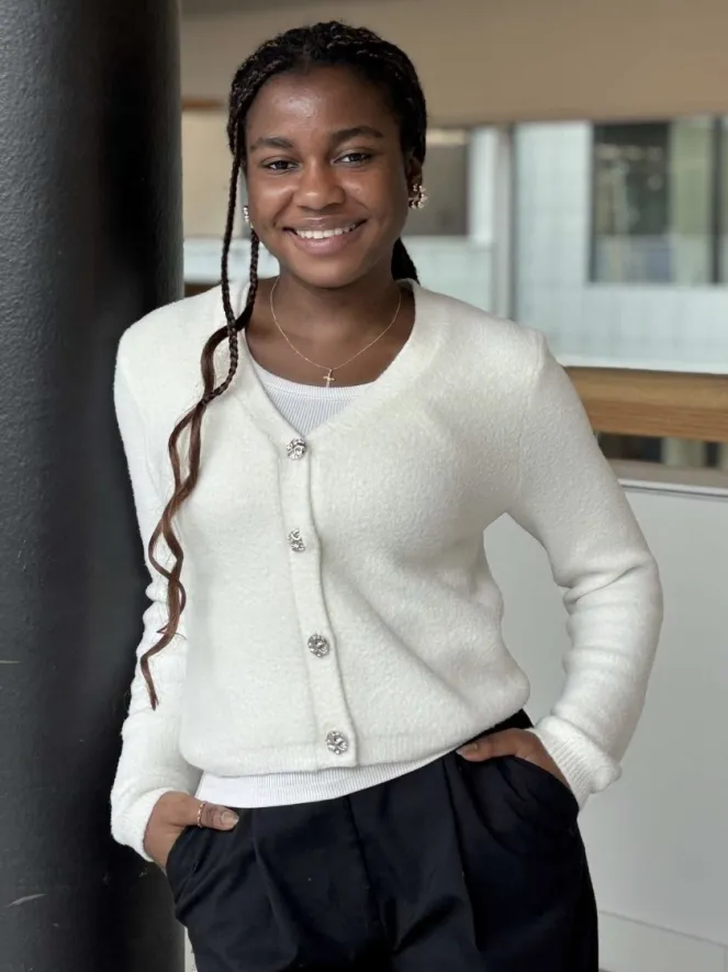 Frau mit braunem Haar, weissem Pullover, angelehnt an Säule