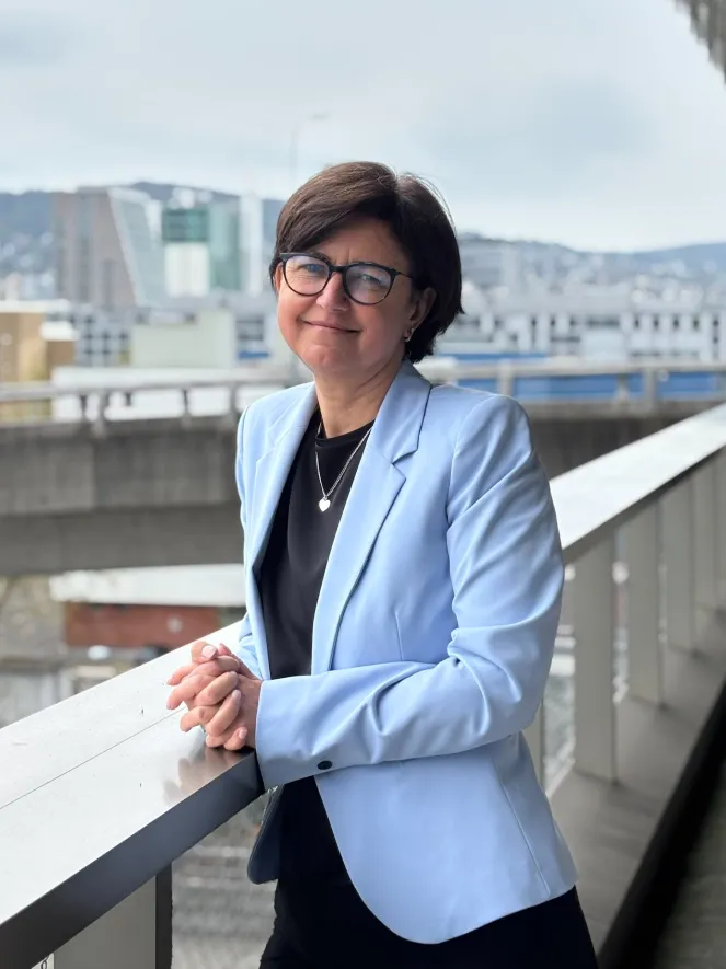 Frau mit braunen Haaren, Brille und hellblauen Blazer