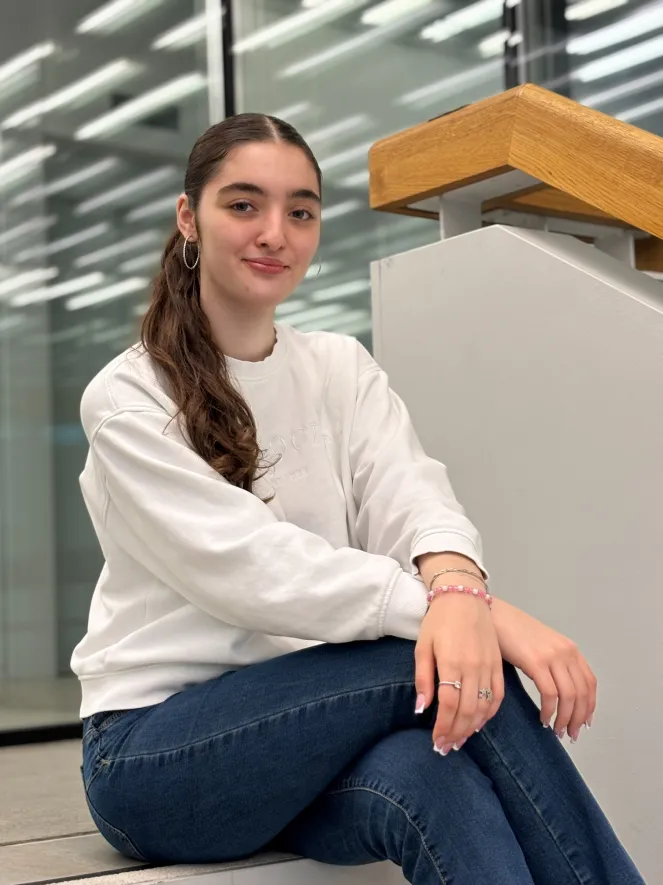 Junge Frau mit braunen Haar, lächelnd, sitzend auf Treppe