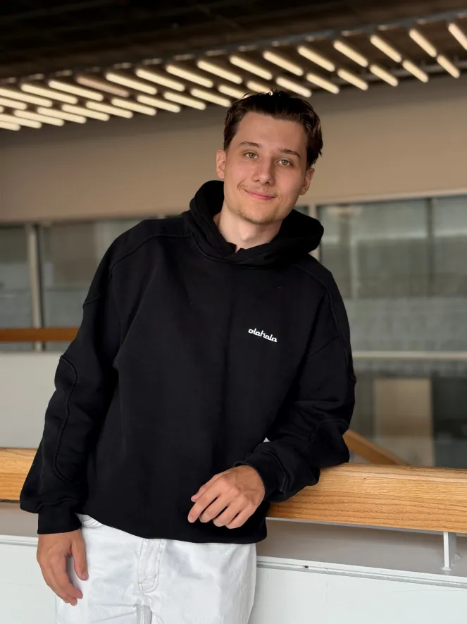 Junger Mann, schwarzer Pulli mit mittellangem Haar