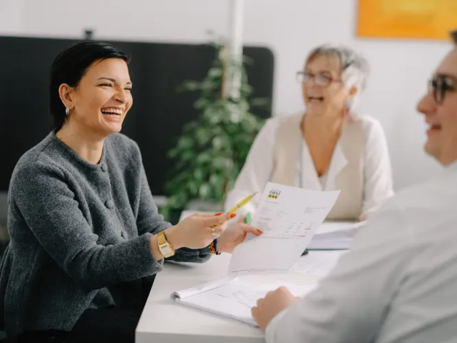 Zwei Frauen lachend am Tisch mit Papier auf dem Tisch