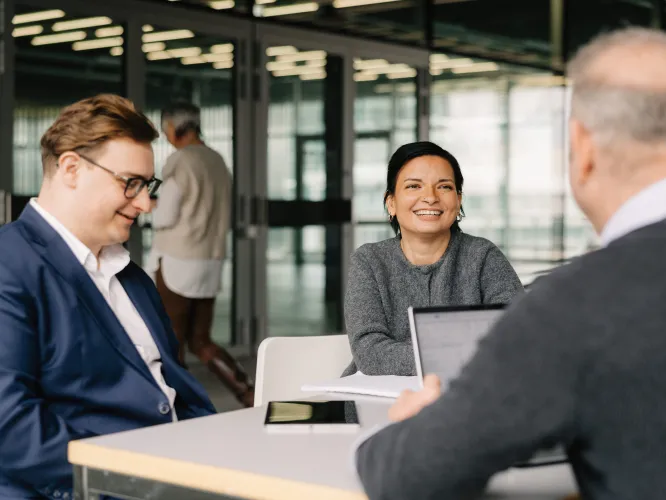 Team lächelnd an einem Tisch mit Laptop