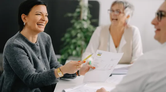 Zwei Frauen lachend am Tisch mit Papier auf dem Tisch