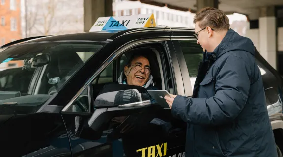 Taxifahrer lacht und schaut zu einem Mann, der ausserhalb des Taxis steht. Das Taxi ist von der Zentrale Taxi 444.